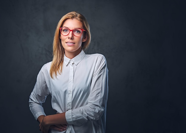 Mujer de negocios rubia atractiva en una camisa blanca sobre fondo gris.