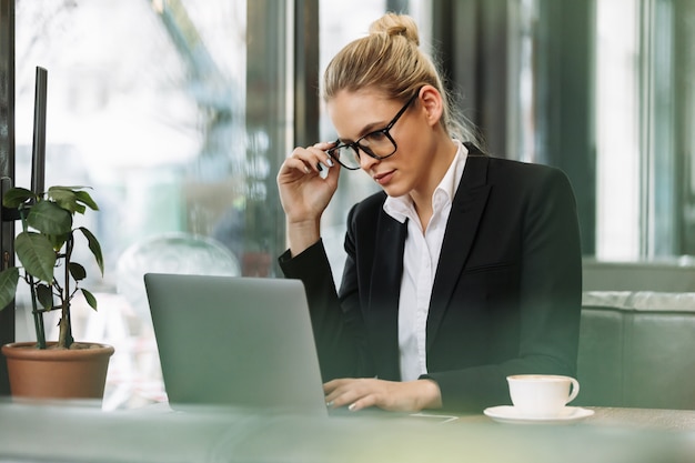 Mujer de negocios rubia concentrada usando la computadora portátil.