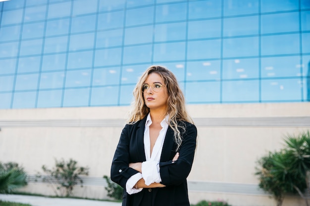 Foto gratuita mujer de negocios rubia enfrente de edificio de cristal