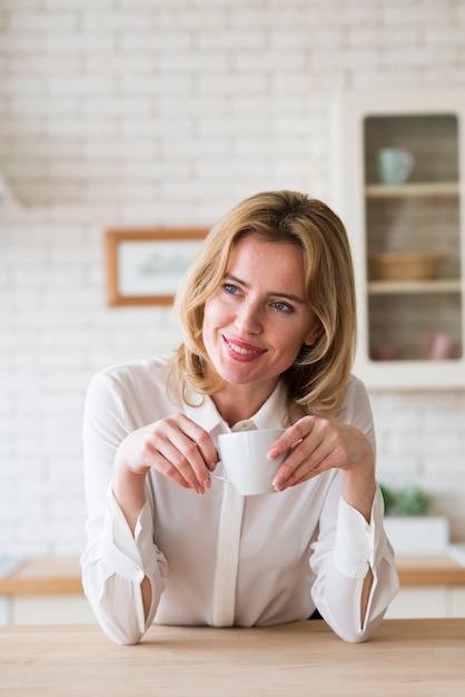 Foto gratuita mujer de negocios rubia que se sienta con la taza de café