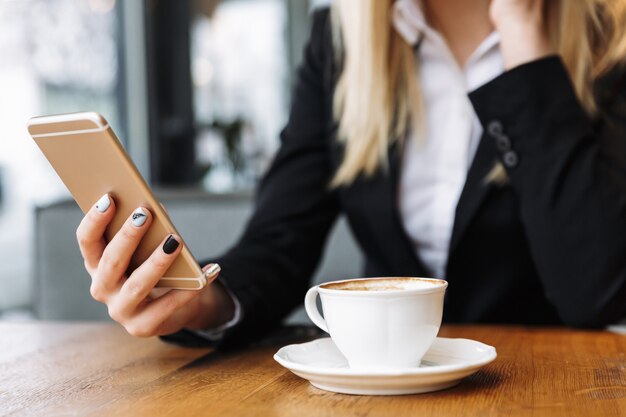 Mujer de negocios rubia sentada en el interior en la cafetería