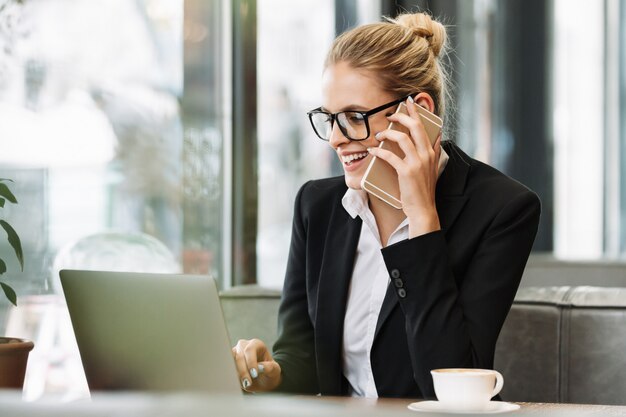 Mujer de negocios rubia sonriente hablando por teléfono móvil