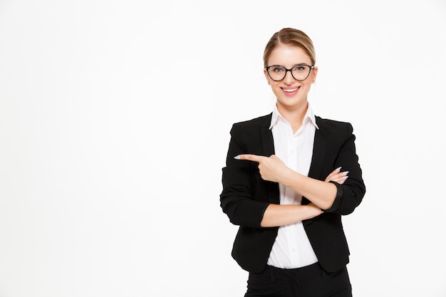 Mujer de negocios rubia sonriente en lentes apuntando lejos