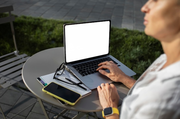 Mujer de negocios rubia trabajando en su computadora portátil al aire libre