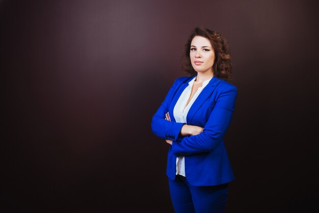 Mujer de negocios seguros de pie en un traje azul con las manos juntas.