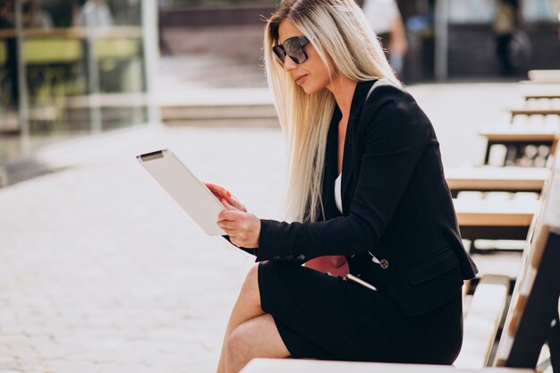 Mujer de negocios sentada en un banco y trabajando en tableta