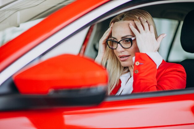 Mujer de negocios sentado en un auto nuevo en una sala de exposición de automóviles