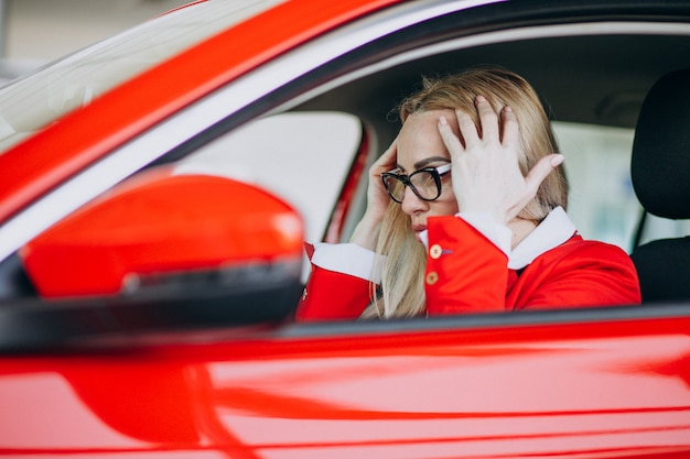 Foto gratuita mujer de negocios sentado en un auto nuevo en una sala de exposición de automóviles