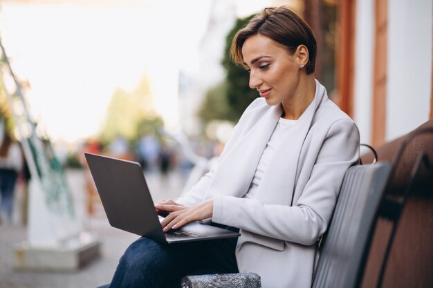 Mujer de negocios sentado en un banco y trabajando en una computadora