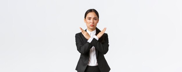 Una mujer de negocios seria y confiada con traje negro que muestra un gesto cruzado para prohibir la acción restringir prohibir o prohibir hacer que cualquier trato deje de funcionar con el fondo blanco del cliente Tiempo de espera