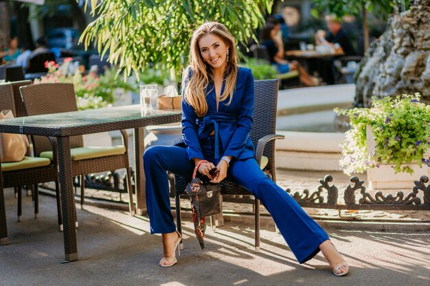 Mujer de negocios sexy con traje azul sentado en la cafetería de verano