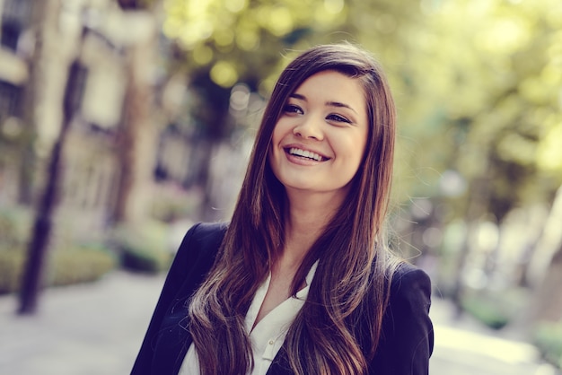 Mujer de negocios sonriente en la ciudad con fondo borroso