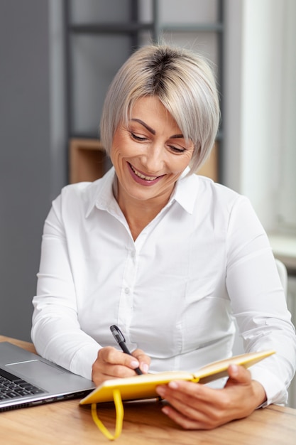 Mujer de negocios sonriente escribiendo en agenda