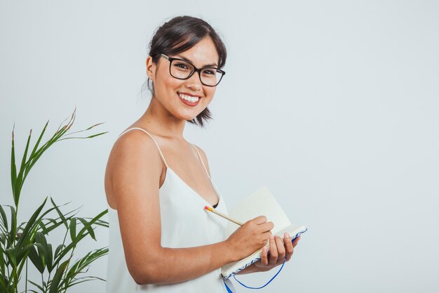 Mujer de negocios sonriente posando y escribiendo en su agenda
