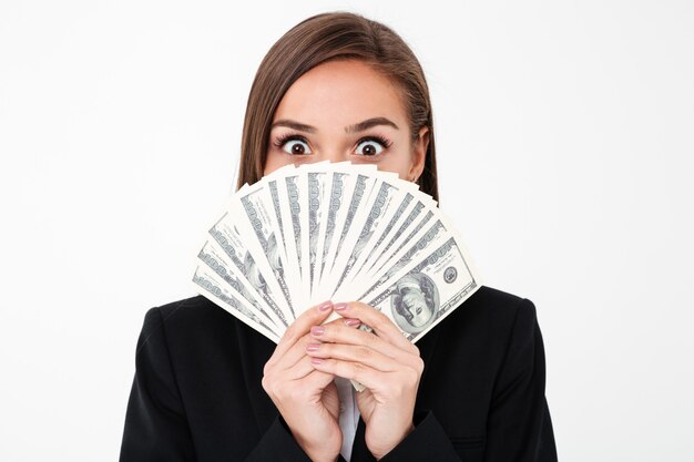 Mujer de negocios sorprendida que cubre la cara con dinero