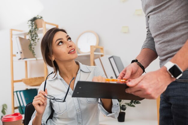 Mujer de negocios sosteniendo sus gafas y un portapapeles