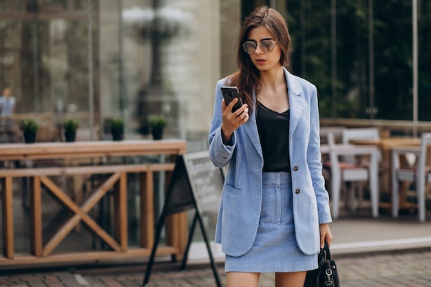 Mujer de negocios con teléfono fuera de la calle