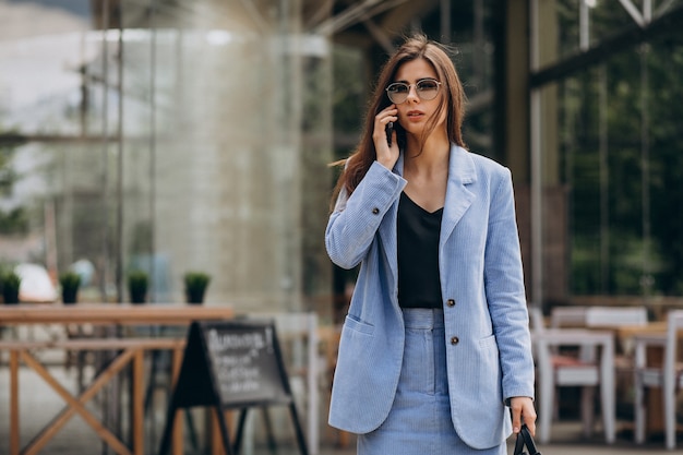 Foto gratuita mujer de negocios con teléfono fuera de la calle