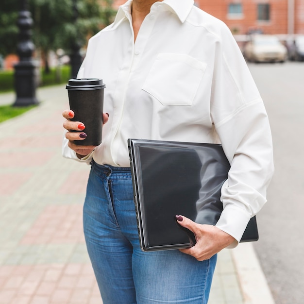 Mujer de negocios, tenencia, computadora portátil, y, café