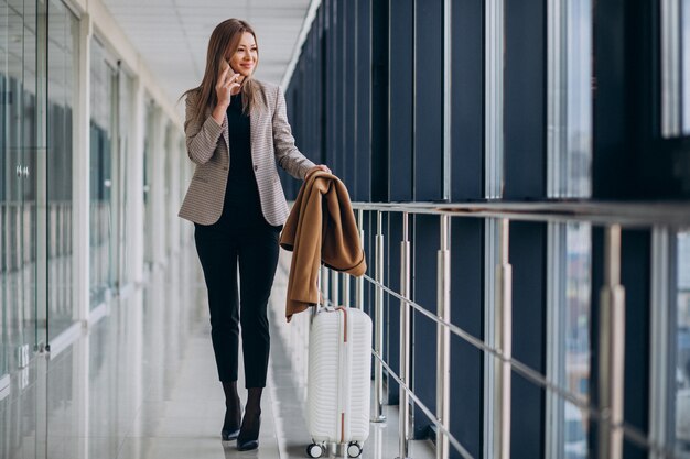 Mujer de negocios en la terminal con bolsa de viaje hablando por teléfono