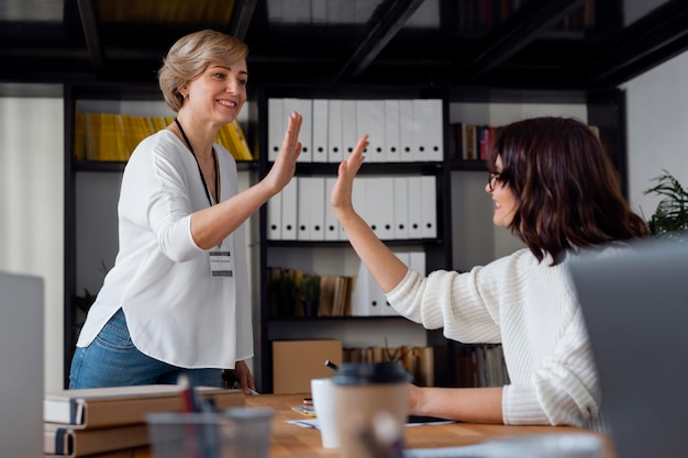 Mujer de negocios de tiro medio choca esos cinco