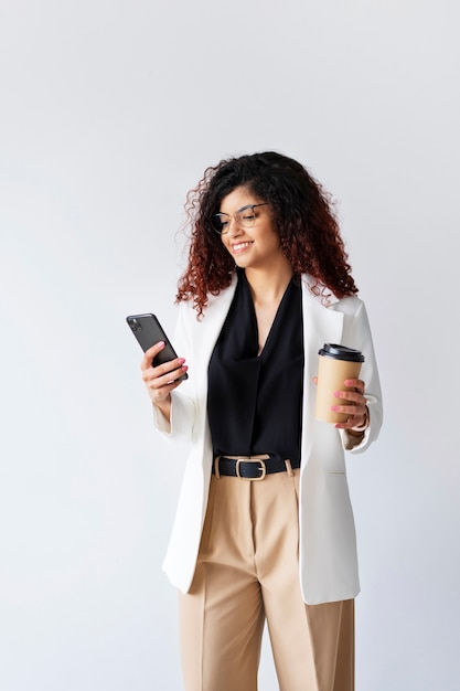 Mujer de negocios de tiro medio sosteniendo teléfono