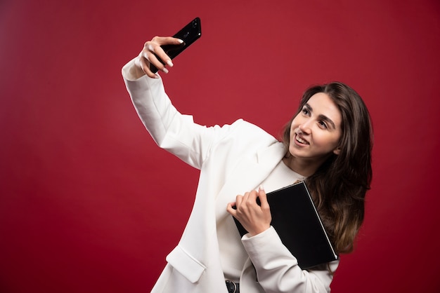 Mujer de negocios tomando un selfie con cuadernos