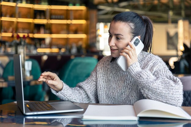 Una mujer de negocios trabaja en un café con una computadora portátil.