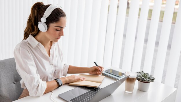 Mujer de negocios, trabajando, con, computadora portátil, y, auriculares