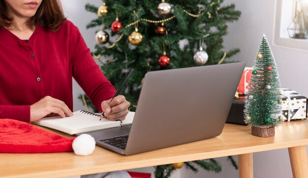 Mujer de negocios trabajando en equipo en el día de Navidad con caja de regalo y fondo de árbol de Navidad.