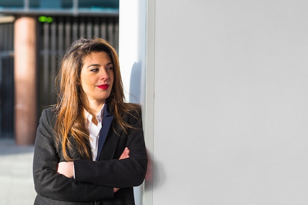 Mujer de negocios en traje apoyado en la pared