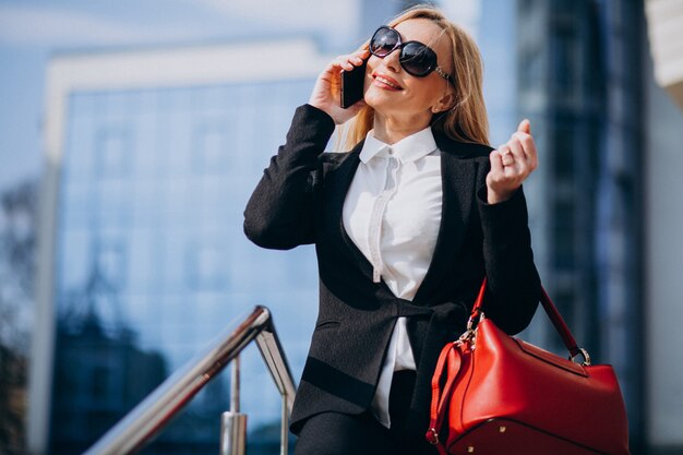 Mujer de negocios en traje elegante hablando por teléfono por el centro de negocios