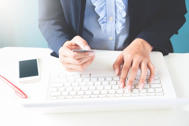 Mujer de negocios en traje oscuro la celebración de tarjeta de crédito y el uso de la computadora portátil, Negocios y el concepto de compras en línea