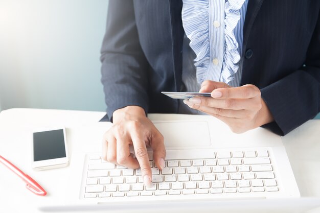 Mujer de negocios en traje oscuro la celebración de tarjeta de crédito y el uso de la computadora portátil, Negocios y el concepto de compras en línea