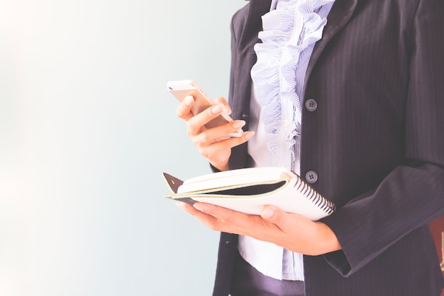 Mujer de negocios en traje oscuro celebración de teléfono móvil y portátil, concepto de negocio con espacio de copia