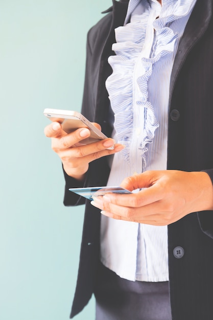 Foto gratuita mujer de negocios en traje oscuro explotación móvil y tarjeta de crédito, negocios y compras en línea concepto