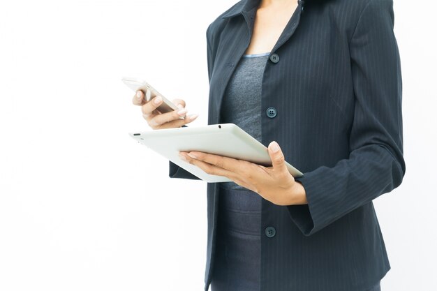 Mujer de negocios en traje oscuro con su tableta y teléfono móvil sobre fondo blanco con espacio de copia
