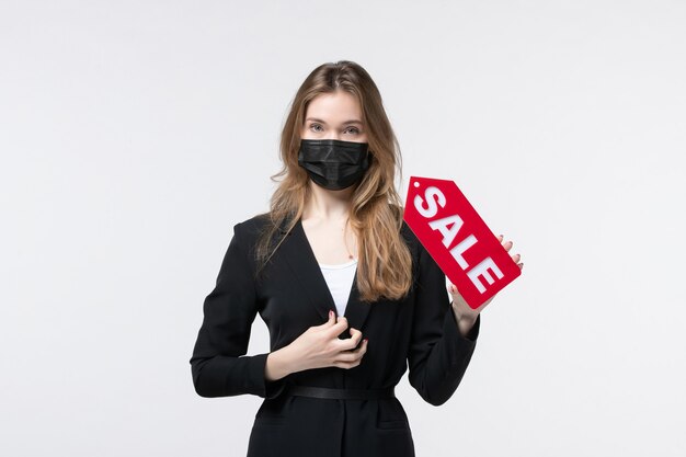 Mujer de negocios en traje con su máscara médica y mostrando la venta posando para la cámara en blanco
