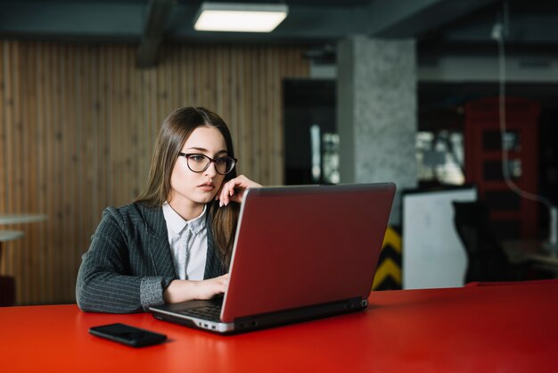 Mujer de negocios en traje usando laptop en mesa