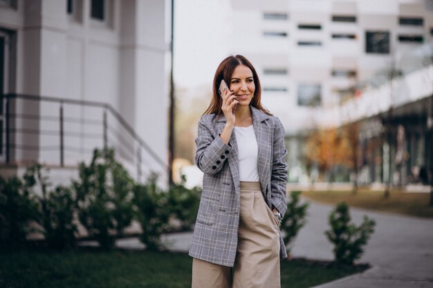 Mujer de negocios usando teléfono afuera en la calle por el edificio
