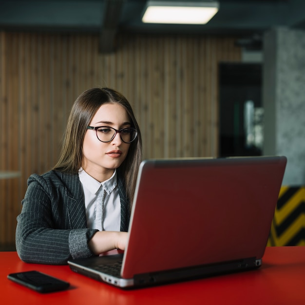 Mujer de negocios, usar la computadora portátil, en la mesa