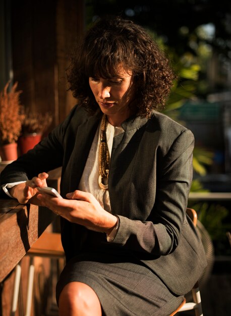 Mujer de negocios, utilizar, teléfono móvil, en, cafetería