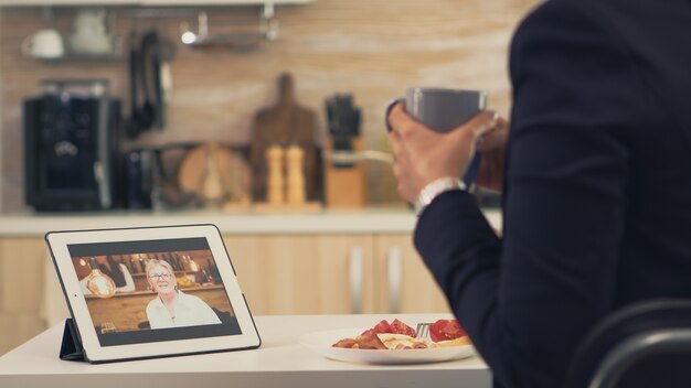 Mujer de negocios en una videollamada con su madre durante el desayuno. Uso de la tecnología web de Internet en línea moderna para chatear a través de la aplicación de videoconferencia con cámara web con parientes, familiares, amigos y compañeros de trabajo