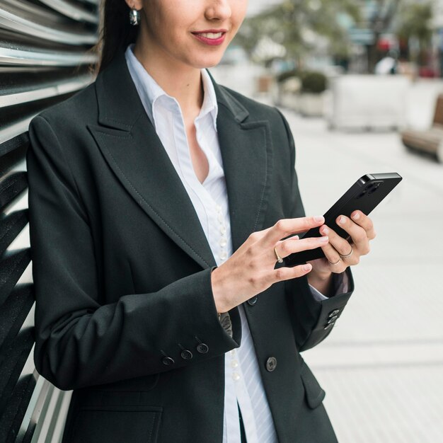 Mujer de negocios de vista frontal comprobando su smartphone