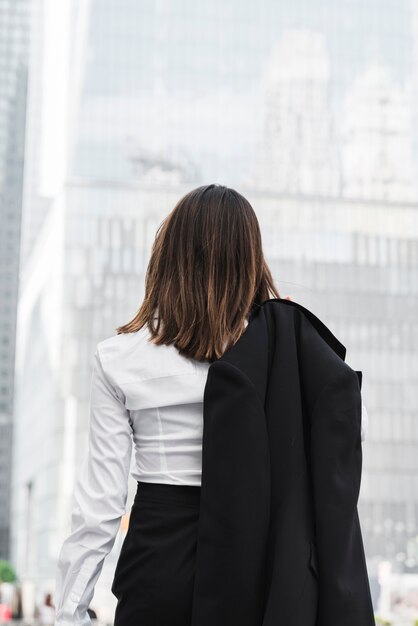 Mujer de negocios vista trasera sosteniendo una chaqueta