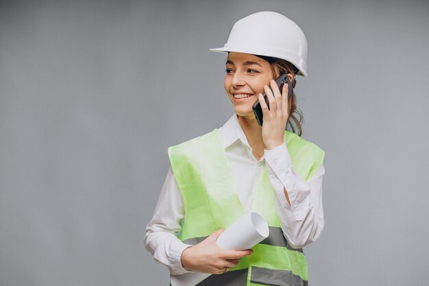 Mujer de negocios vistiendo chaleco y casco hablando por teléfono