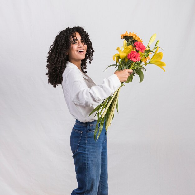 Mujer negra alegre que sostiene el ramo de las flores