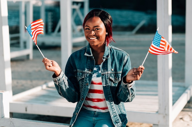 Mujer negra con banderas americanas sentadas en la playa