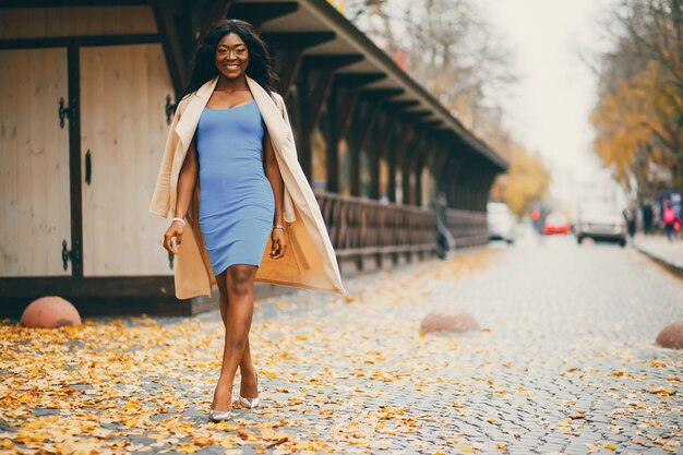 Mujer negra caminando en una ciudad de otoño