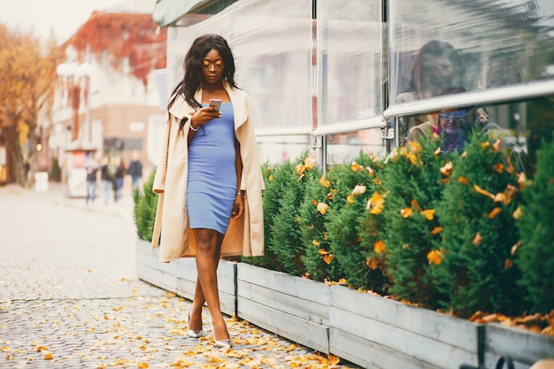 Mujer negra caminando en una ciudad de otoño